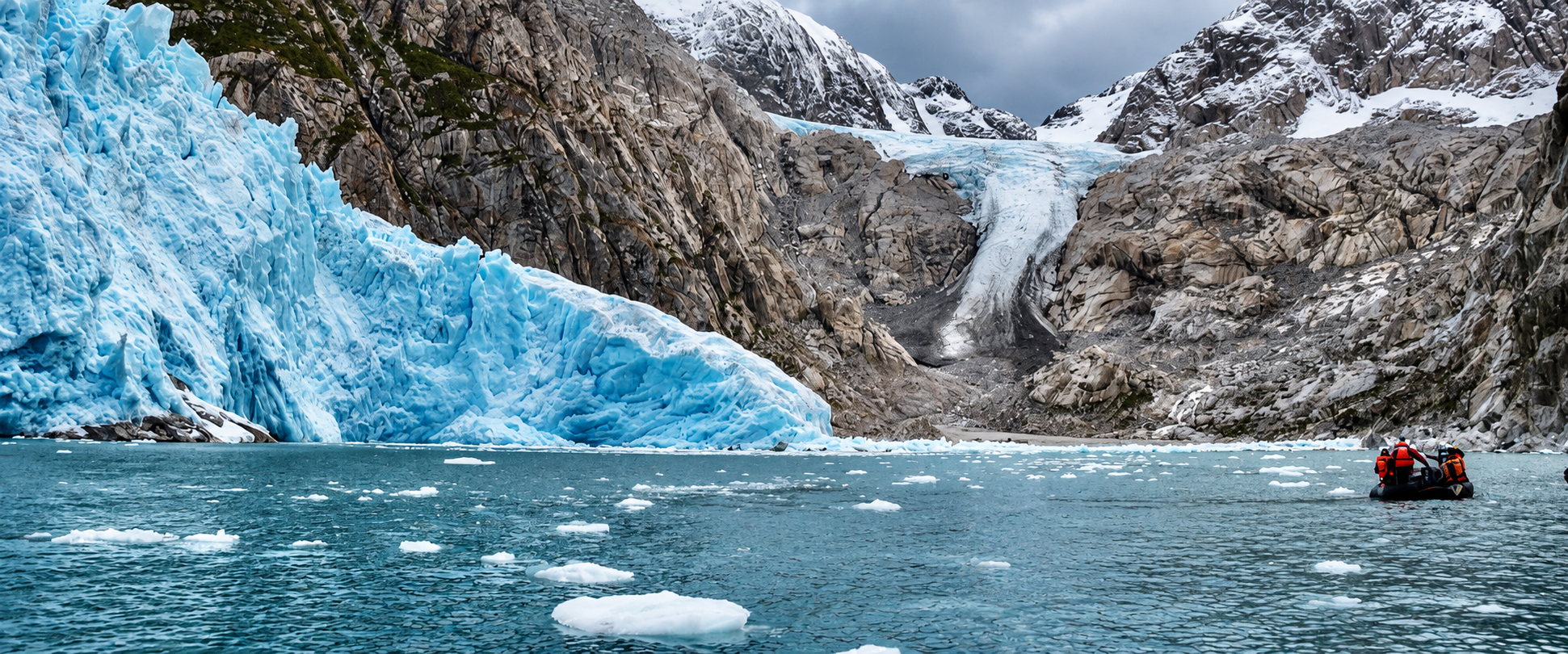 A small Zodiac approaches blue glacier ice beneath steep mountains in the Patagonian channels