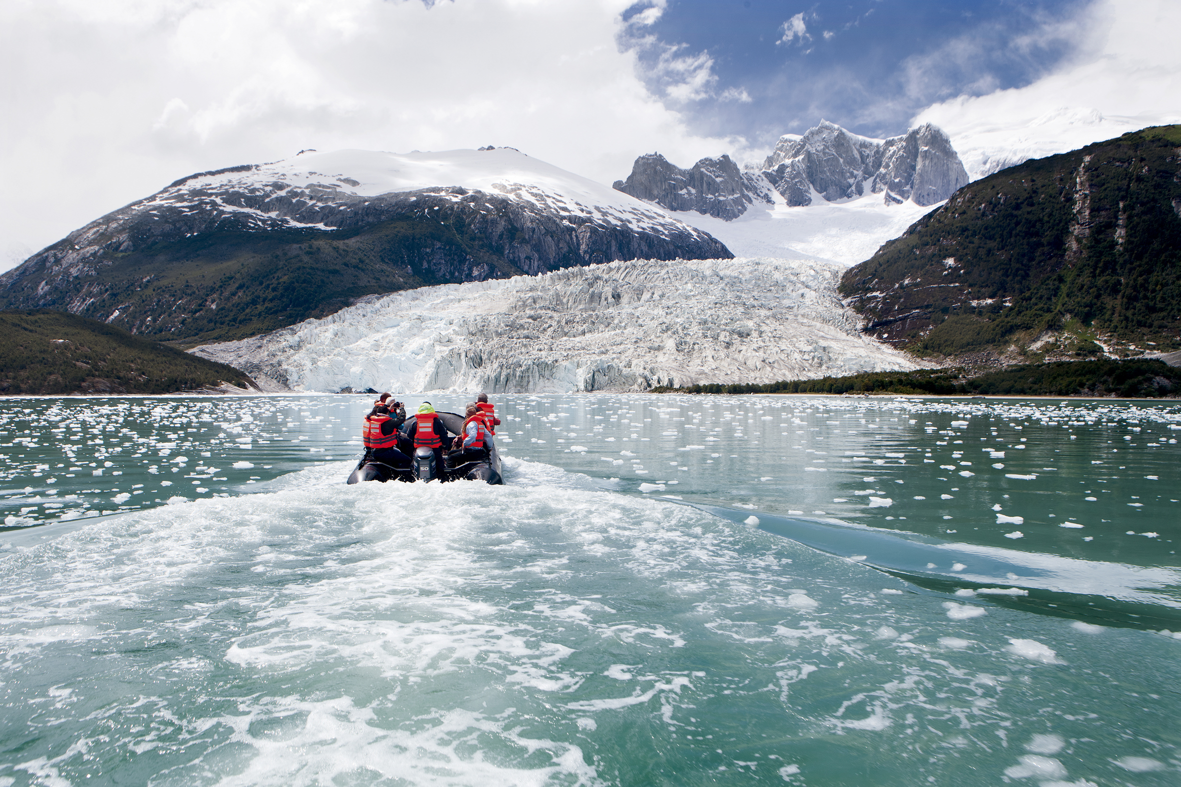 Travelers in a Zodiac approaching Pia Glacier across turquoise water